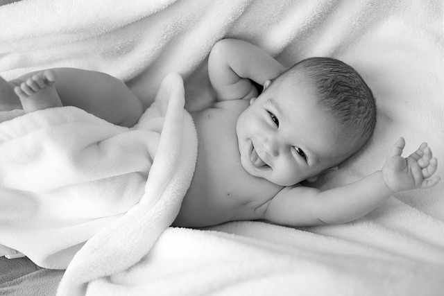 Infant child looking happily towards the camera as it wriggles in a bed